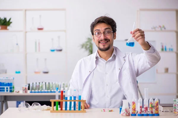 Young male chemist in drugs synthesis concept