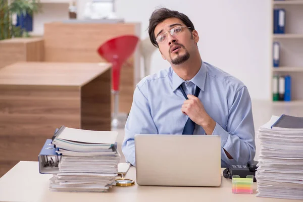 Joven empleado masculino y demasiado trabajo en la oficina — Foto de Stock