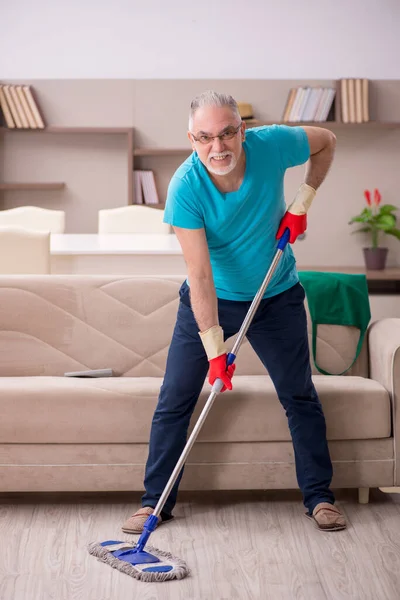 Oude man die het huis schoonmaakt — Stockfoto