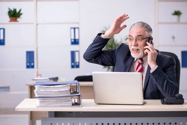 Homem velho empregado sentado no local de trabalho — Fotografia de Stock