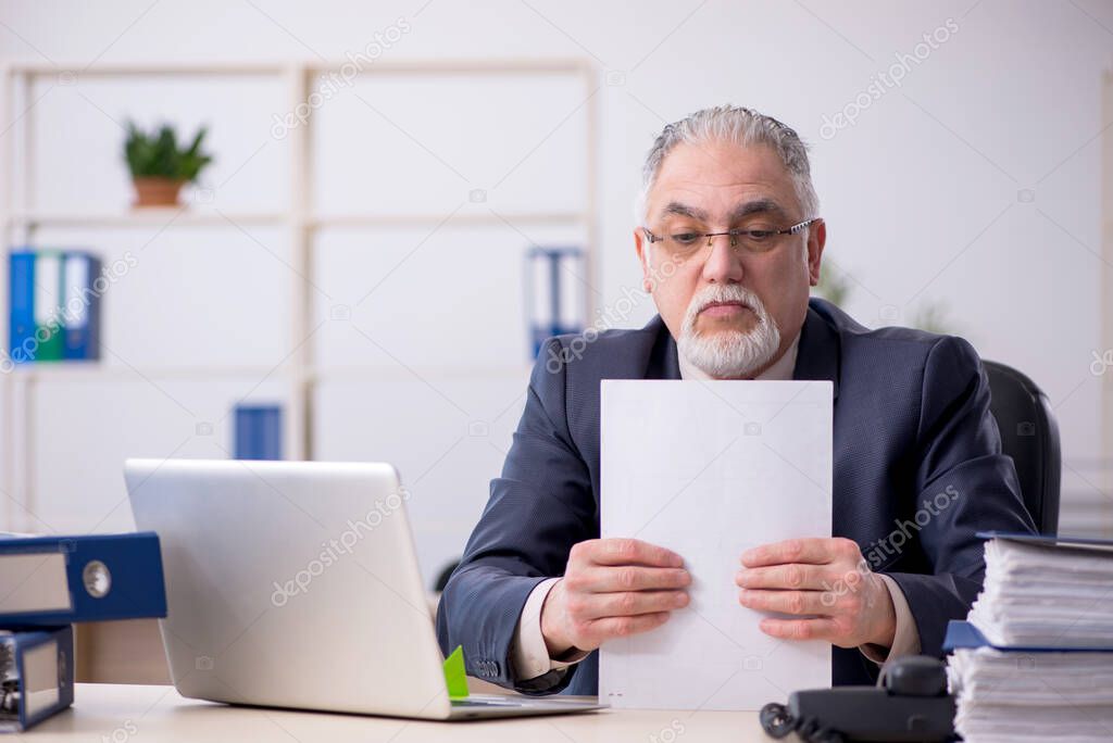 Old male employee sitting at workplace