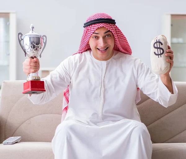 Arab man with prize and money on sofa — Stock Photo, Image