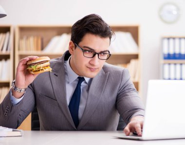 Aç komik iş adamı abur cubur sandviç yiyor.