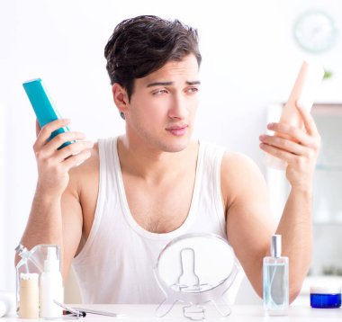 Genç yakışıklı adam aynaya bakıyor.