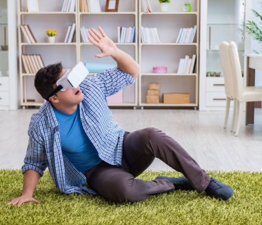 Evde sanal gerçeklik gözlüklü bir adam oynuyor.