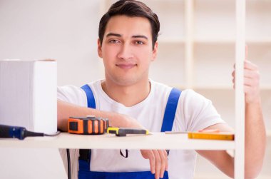 İşçi adam montaj kitaplığını tamir ediyor