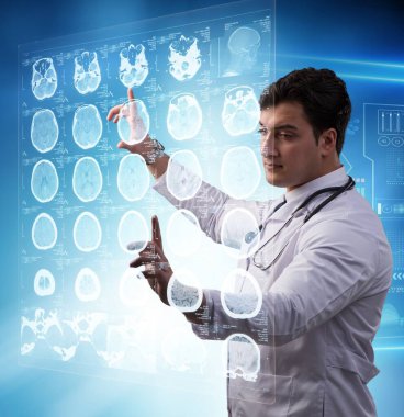 Erkek doktor MRI taramasının röntgenini çekiyor.