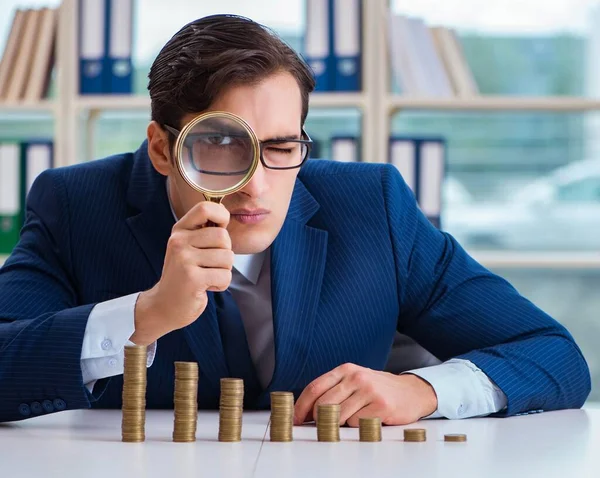 Homme d'affaires avec des piles de pièces dans le bureau — Photo