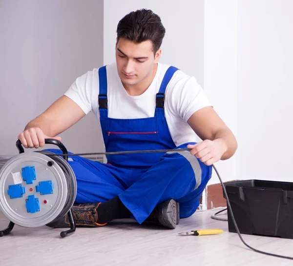 Young electrician working on socket at home