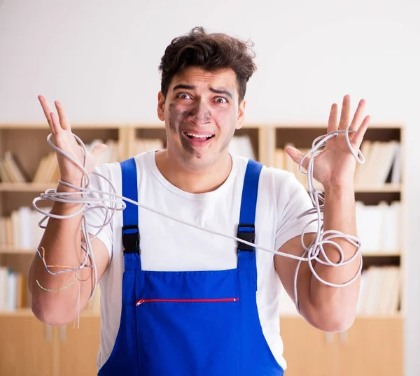 Funny young electrician tangled in cables — Stock Photo, Image