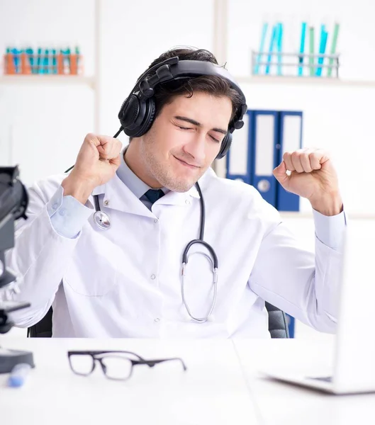 Happy excited doctor listening to music during lunch break in ho