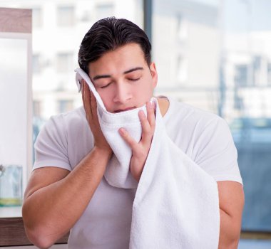 Genç yakışıklı adam yüz kremi sürüyor.