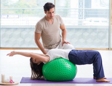 Kişisel koç, jimnastik salonunda denge topuyla kadınlara yardım ediyor.