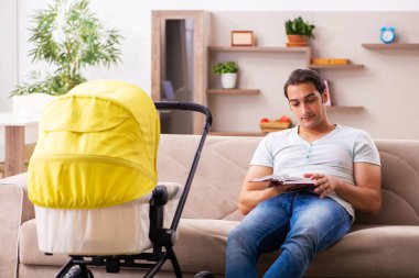 Genç erkek müteahhit evde yeni doğan çocuğa bakıyor.