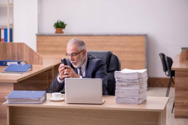 Ofisteki aşırı işten memnun olmayan yaşlı bir erkek işçi.