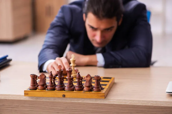 Joven empleado masculino jugando ajedrez en el lugar de trabajo — Foto de Stock