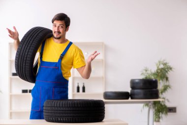 Atölyede lastiği olan genç bir erkek tamirci.