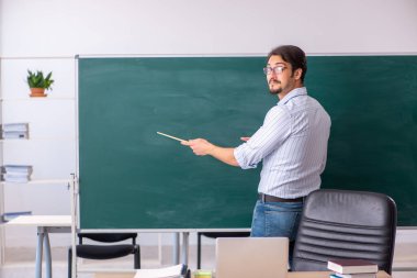 Tahtanın önündeki genç erkek öğretmen.