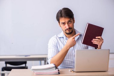 Genç erkek öğretmen beyaz tahtanın önünde.