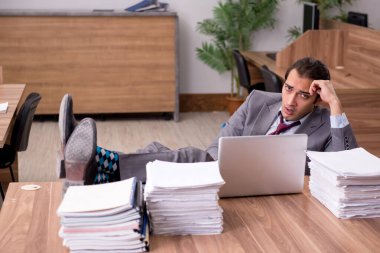 Ofisteki aşırı işten memnun olmayan genç bir erkek işçi.