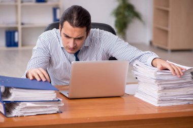 Ofisteki aşırı işten memnun olmayan genç bir erkek işçi.