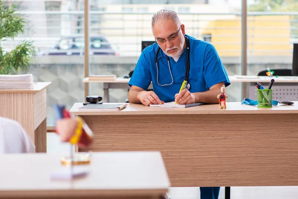 Old male doctor working in the clinic — Stock Photo, Image