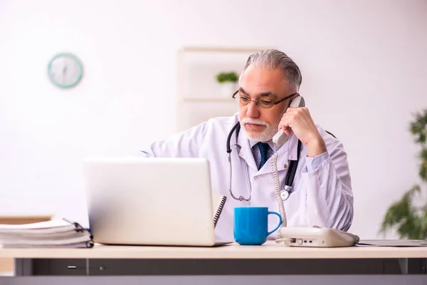 Klinikte çalışan yaşlı erkek doktor. — Stok fotoğraf