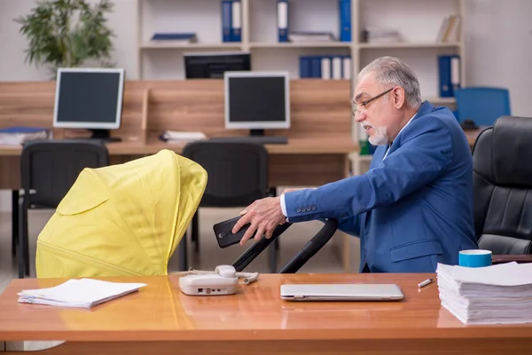 Aged businessman employee looking after newborn at workplace — Stock Photo, Image