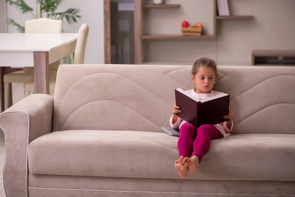 Liten flicka läser bok hemma — Stockfoto