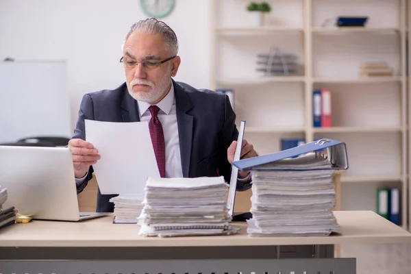 Empleado de edad avanzada y demasiado trabajo en el lugar de trabajo — Foto de Stock