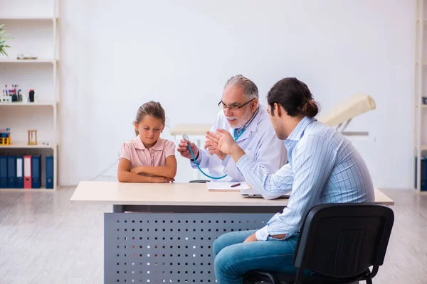 Piccola ragazza con suo padre in visita vecchio medico maschio — Foto Stock