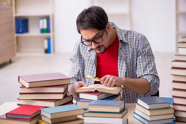 Mladý muž student a příliš mnoho knih ve třídě — Stock fotografie