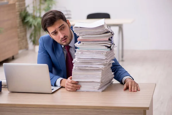 Ung manlig anställd och för mycket arbete på kontoret — Stockfoto