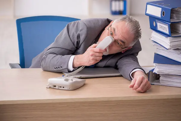 Oude mannelijke werknemer ongelukkig met overmatig werk in het kantoor — Stockfoto