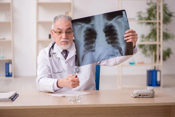 Старый врач-рентгенолог, работающий в клинике во время пандемии — стоковое фото