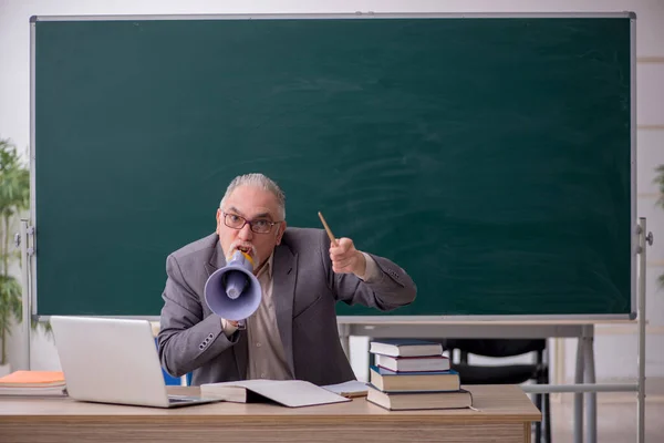 Velho professor do sexo masculino segurando megafone na frente de quadro negro — Fotografia de Stock