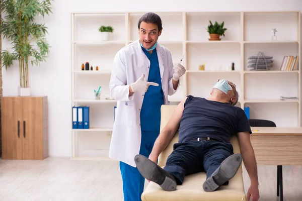 Old man visiting young doctor in covid-19 vaccination concept — Stock Photo, Image