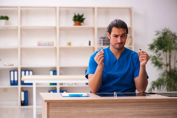 Mladý lékař drží injekční stříkačku na klinice — Stock fotografie