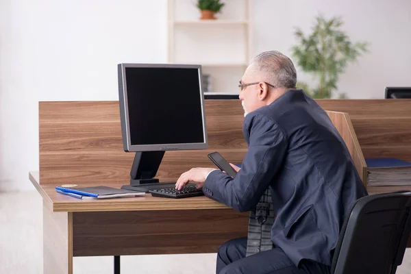 У віці чоловік працівник сидить на робочому місці — стокове фото