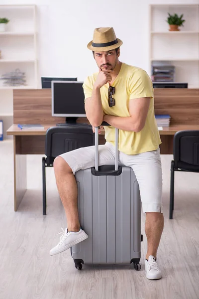 Joven empleado masculino preparándose para el viaje en el lugar de trabajo —  Fotos de Stock