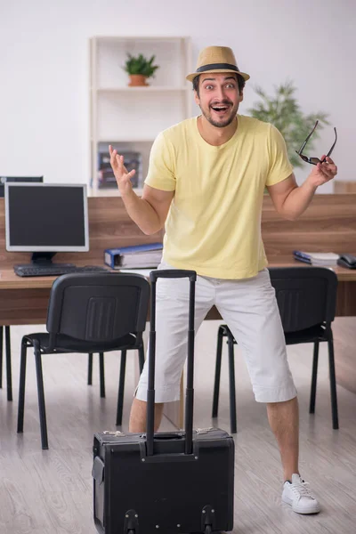 Joven empleado masculino preparándose para el viaje en el lugar de trabajo — Foto de Stock