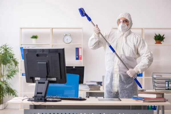 Velho empreiteiro masculino no conceito de desinfecção de escritório — Fotografia de Stock