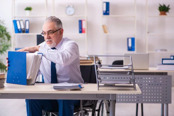 Homem velho empregado em cadeira de rodas sentado no escritório — Fotografia de Stock