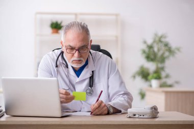 Klinikte çalışan yaşlı erkek doktor.