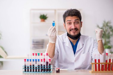 Genç erkek biyokimyacı kan örneklerini pandemik konseptte test ediyor.
