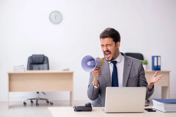 Joven empleado masculino sosteniendo megáfono en el lugar de trabajo — Foto de Stock