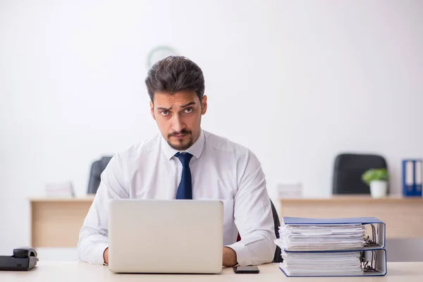 Ung manlig anställd och för mycket arbete på kontoret — Stockfoto