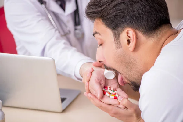 Old male doctor suggesting pills to young male patient