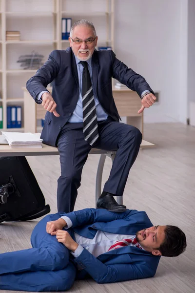 Old boss and young male employee in bullying concept — Stock Photo, Image