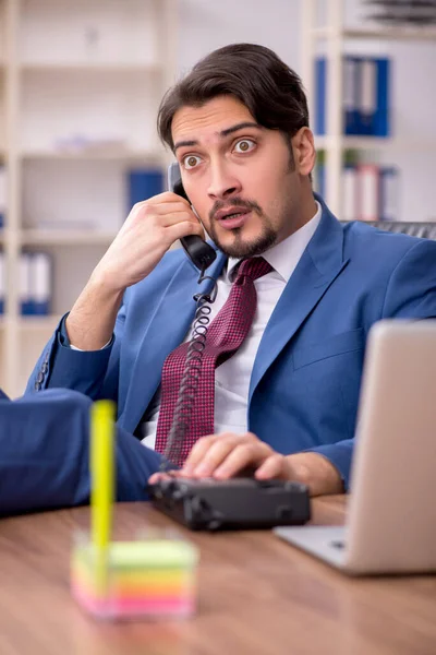 Empleado joven sentado en el lugar de trabajo — Foto de Stock